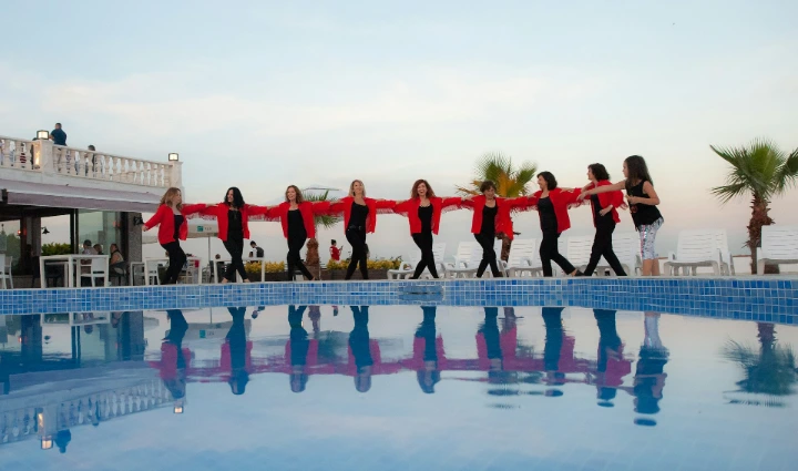 A group of women standing next to a swimming pool
